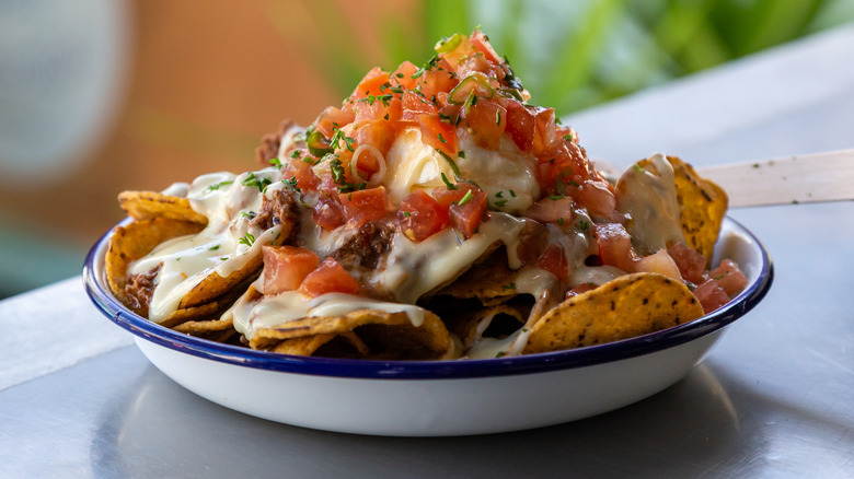 Plate of nachos topped with diced tomatoes