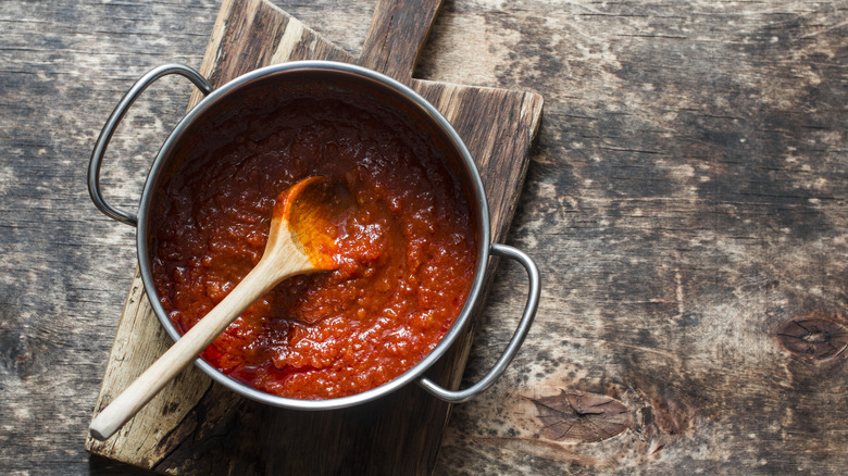 Crushed tomatoes in pan with wooden spoon