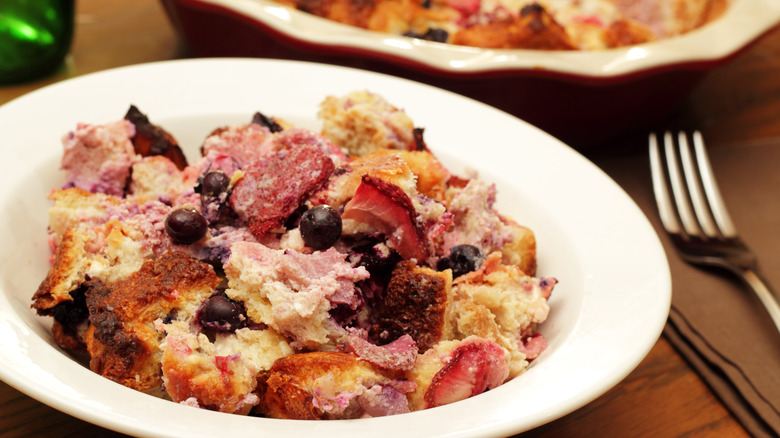 a plate of sweet breakfast casserole with blueberries and strawberries and fork 