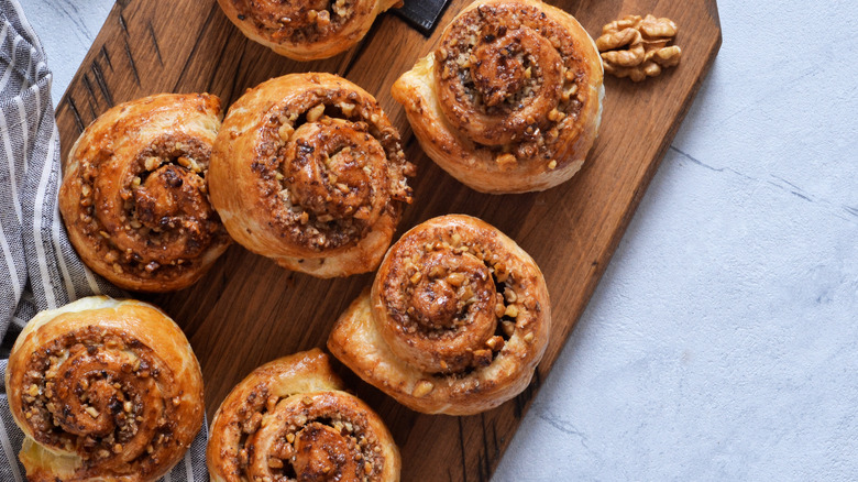cinnamon rolls on a serving board, topped with chopped walnuts