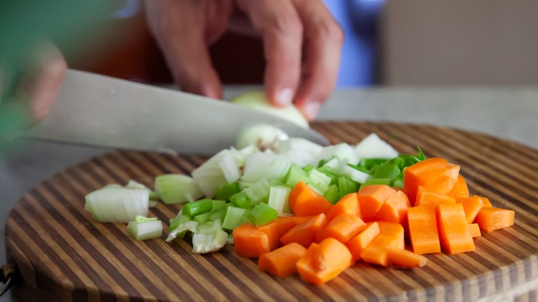 hands chopped mirepoix on board