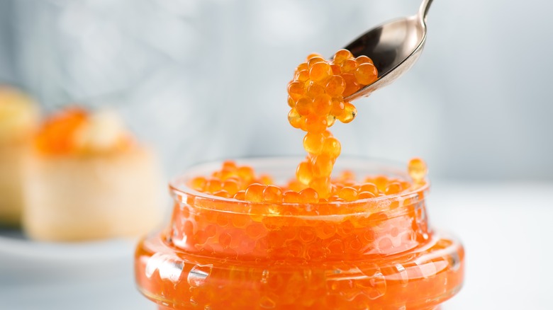 Spoon scooping fish roe out of a jar