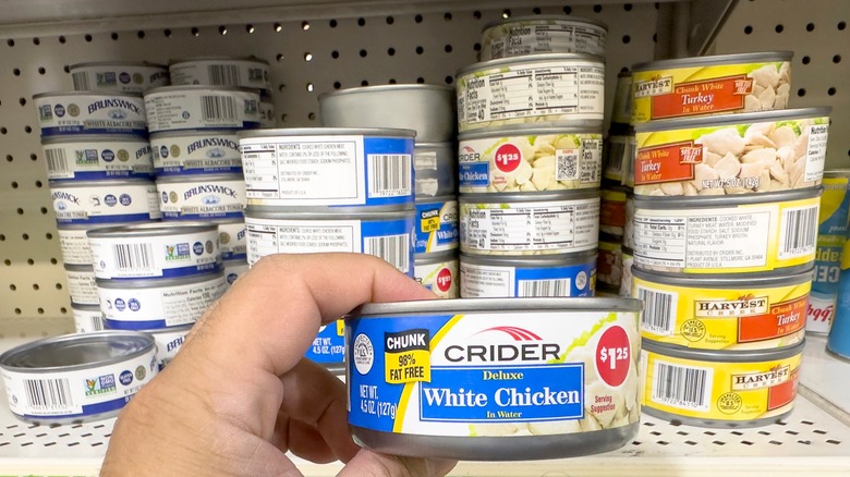 Hand selecting can of chicken at store