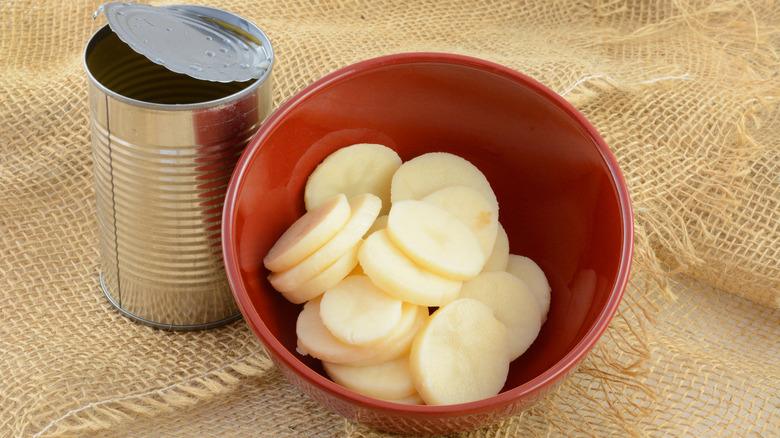 Bowl of sliced canned potatoes next to open tin