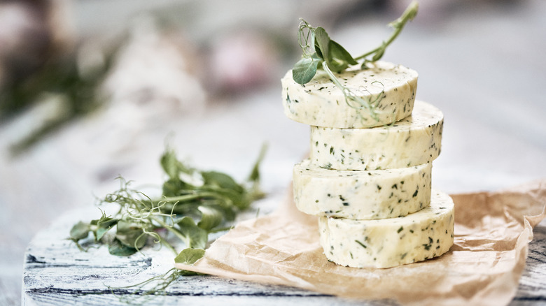 Stacked discs of seasoned butter with fresh herbs