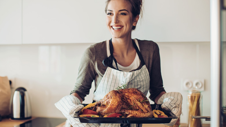 Woman holding roasted turkey on sheet pan