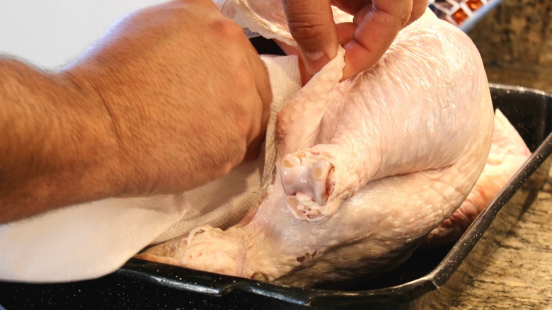 Man using paper towel to dry the inside of a turkey