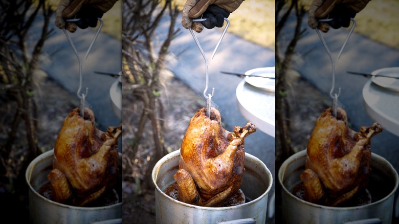 Pulling a cooked turkey out of a deep-fryer