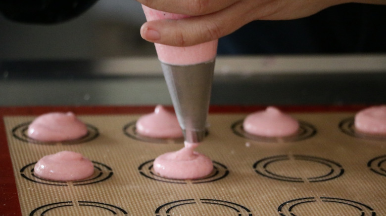 person piping macarons