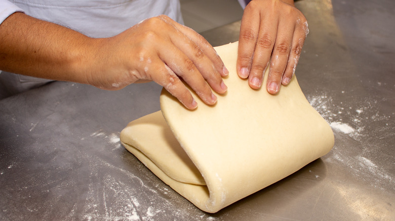 person folding puff pastry dough