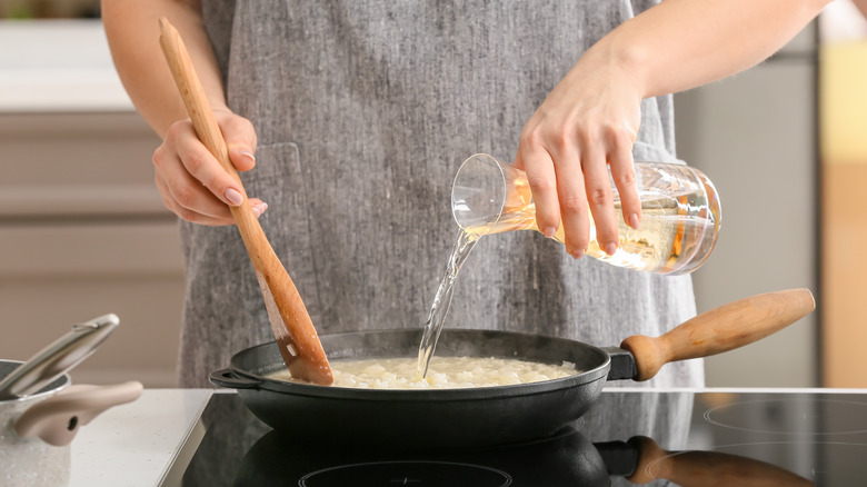 woman stirring wine into risotto