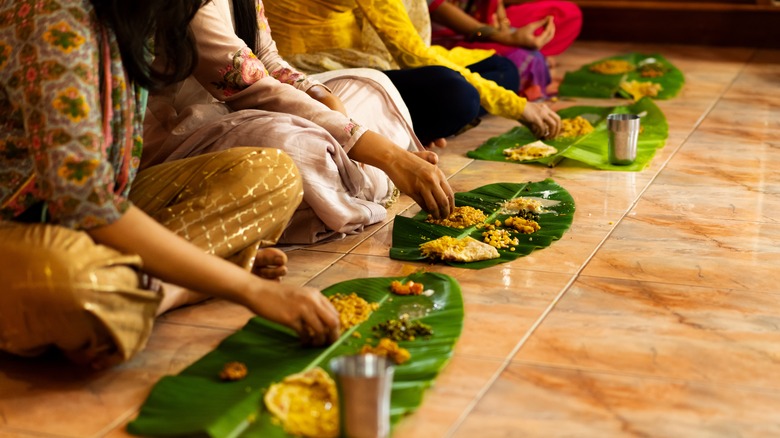 Women sitting on floor and eating Indian food with hands