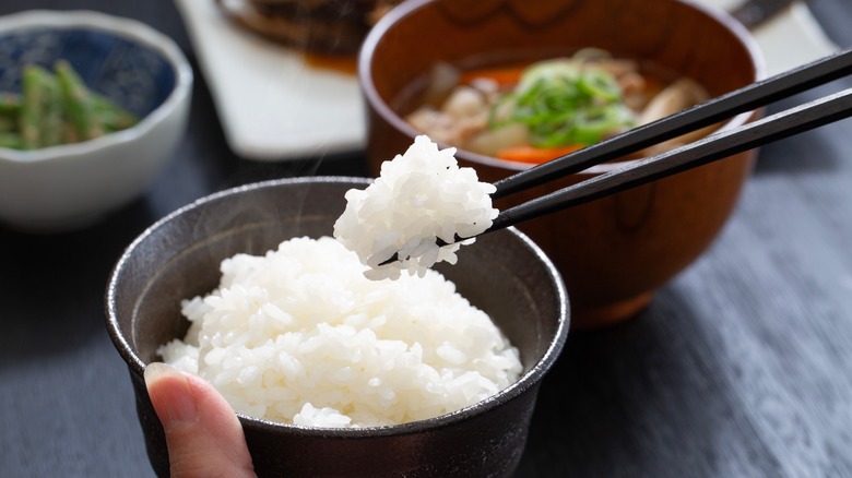 Chopsticks grabbing a bite of white rice from a bowl