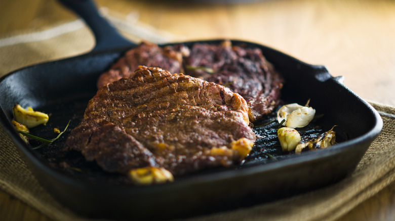 Steak in cast iron skillet with garlic cloves