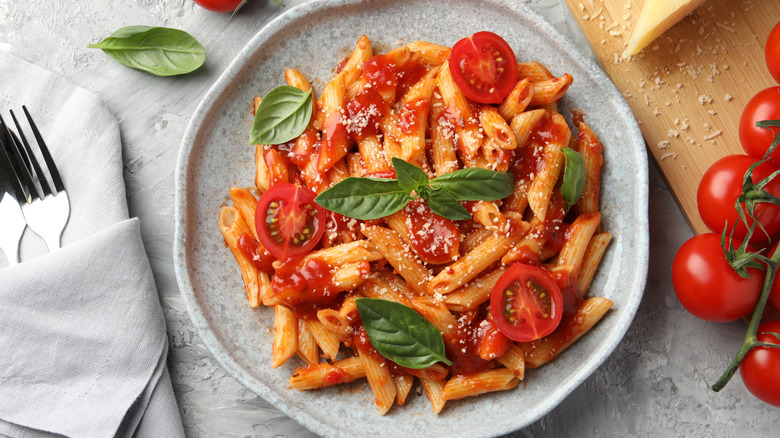 Plate of penne pasta with fresh tomatoes and basil