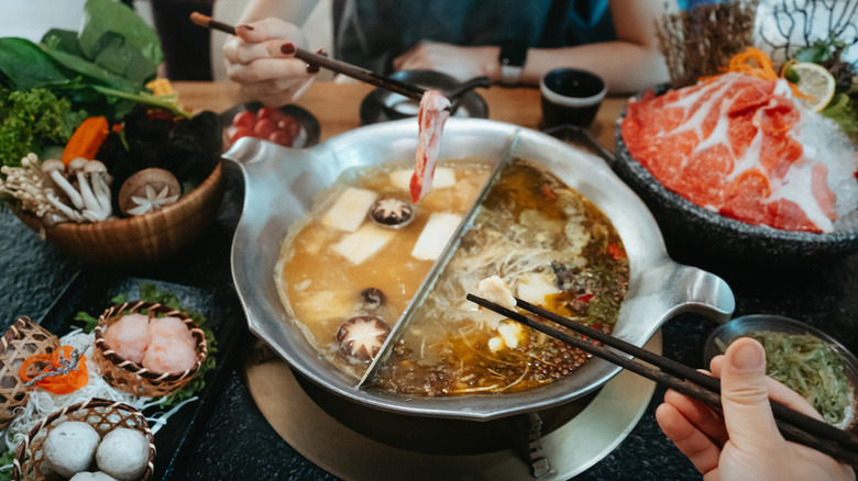 Hot pot broth surrounded by various meats and veggies