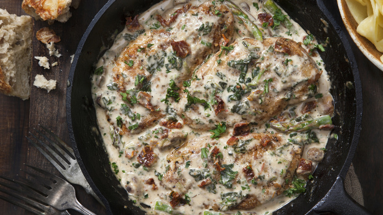 Cast iron pan of chicken in cream sauce with sun-dried tomatoes