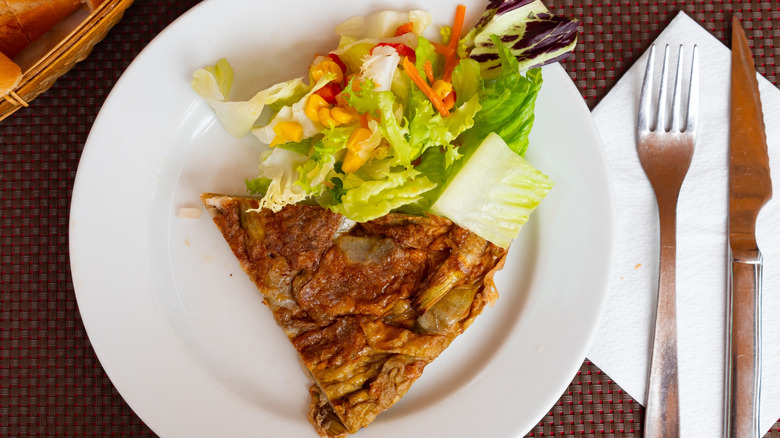 Tortilla de alcachofas on plate with salad