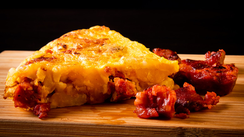 Slice of Spanish omelet with chorizo on cutting board