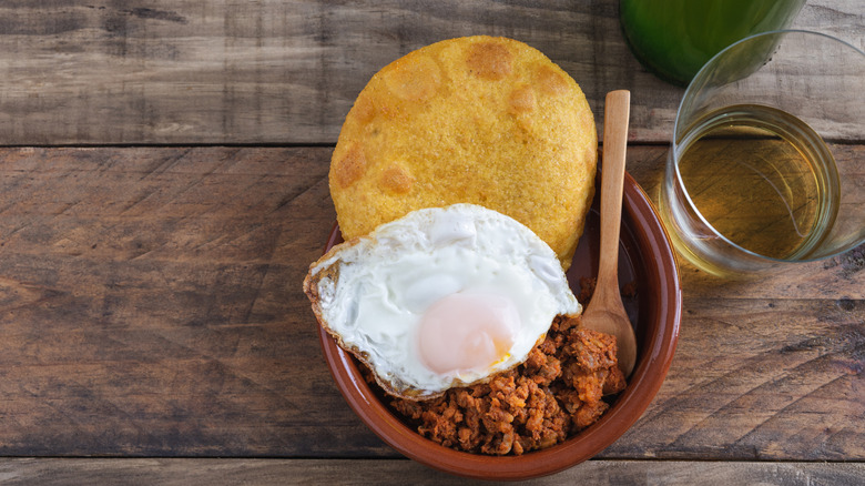 Corn tortos with picadillo and fried egg on a wooden base