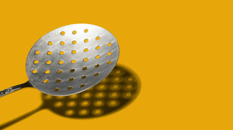 slotted spoon on yellow background