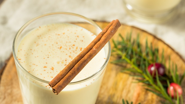 a close up of the top of a glass of eggnog with a cinnamon scroll on top