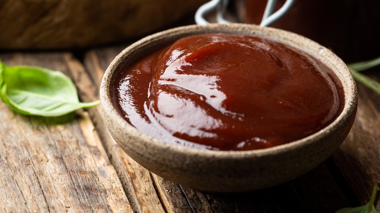 Barbecue sauce in bowl with fresh herbs