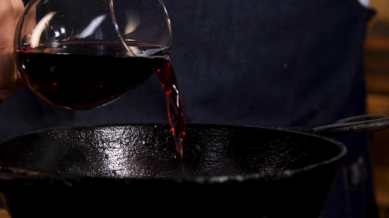 Pouring red wine into cast iron pan