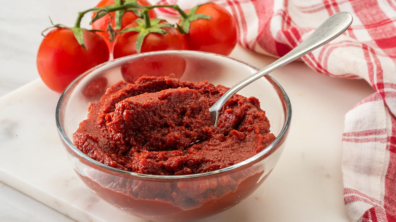 Bowl of tomato paste with fresh tomatoes alongside