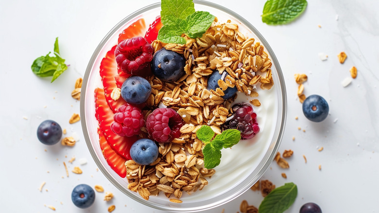 Bowl of homemade granola with yogurt, fresh berries, and mint