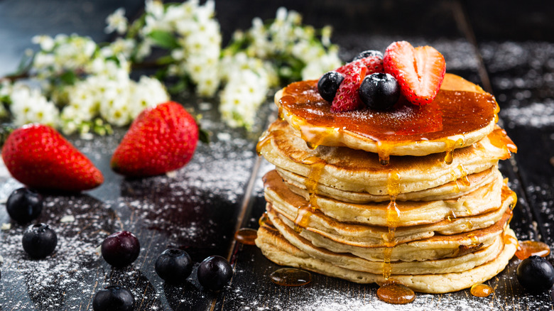 Stack of fluffy pancakes with fresh fruit and syrup