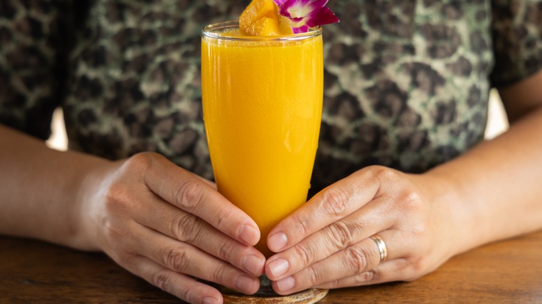 hands holding mango smoothie