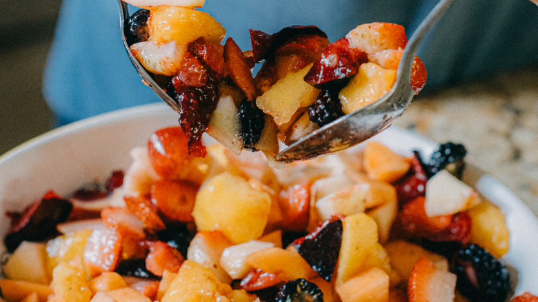 spoons mixing fruit salad