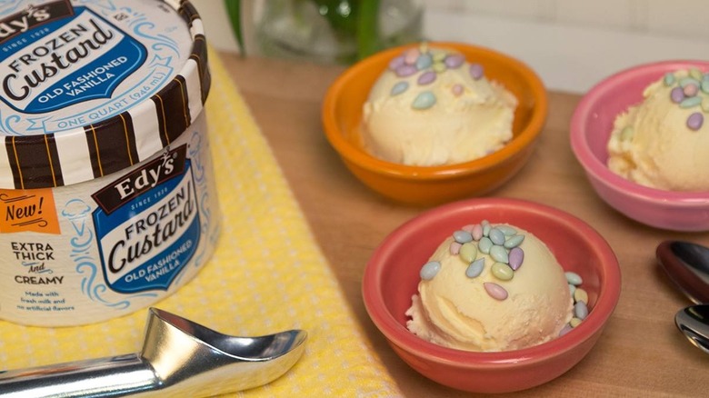 Scoops of vanilla ice cream in bowls beside a carton of Edy's Frozen Custard