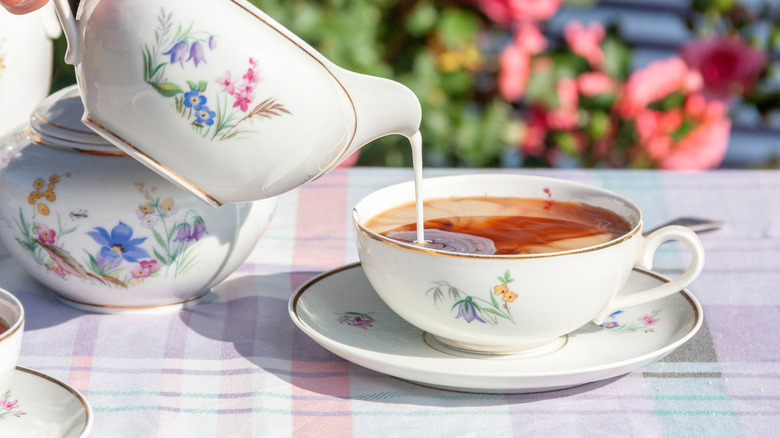 milk being poured into a cup of tea