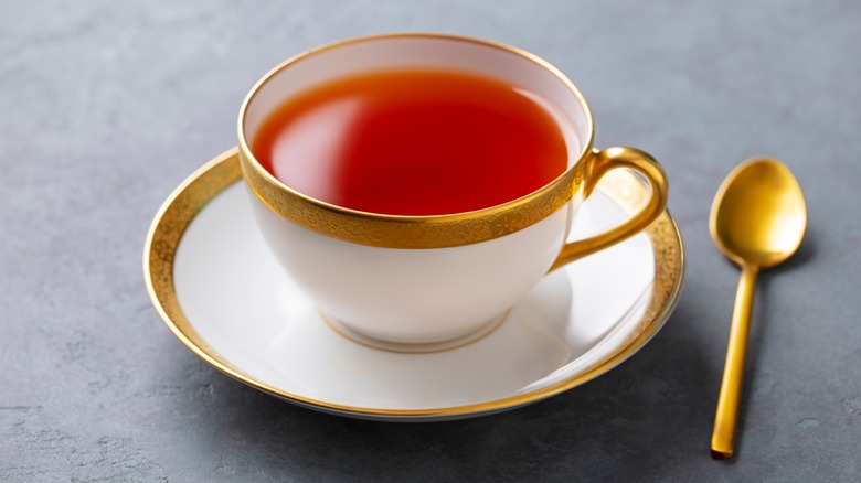 gold-rimmed teacup and saucer and gold teaspoon