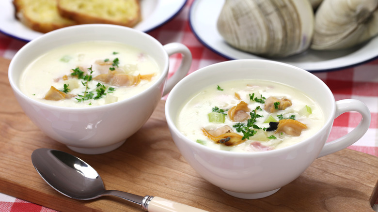 Two large mugs of clam chowder with fresh herbs