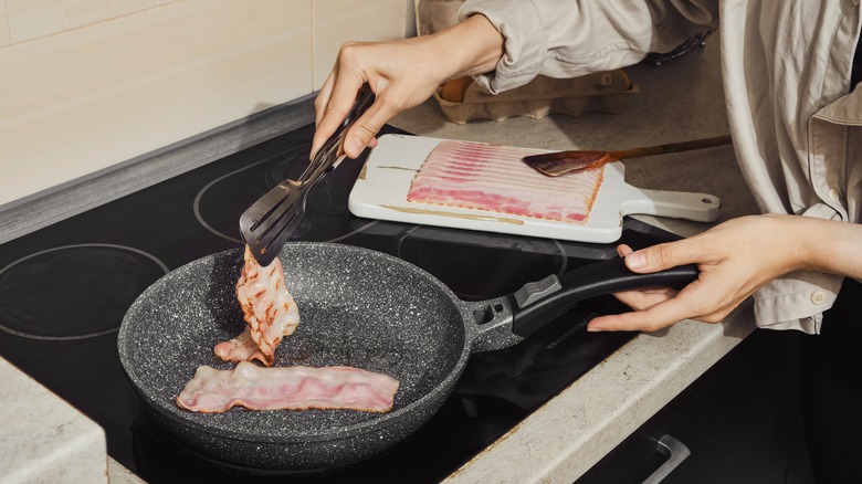 woman flipping bacon in pan