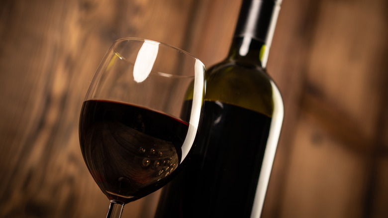 close up of a glass and bottle of dark red wine
