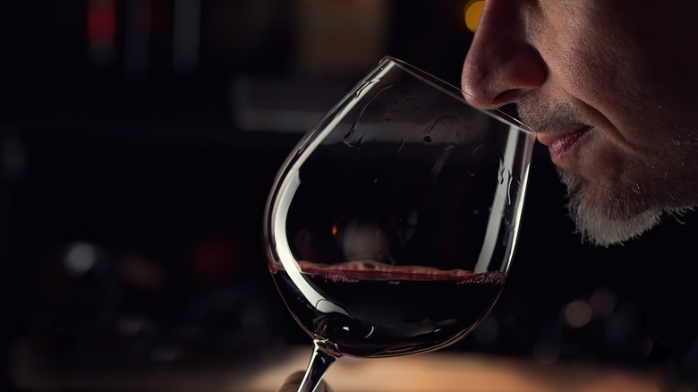 close up of man sniffing a class of red wine