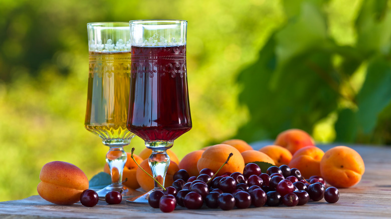 two glasses of sweet wine next to cherries and apricots