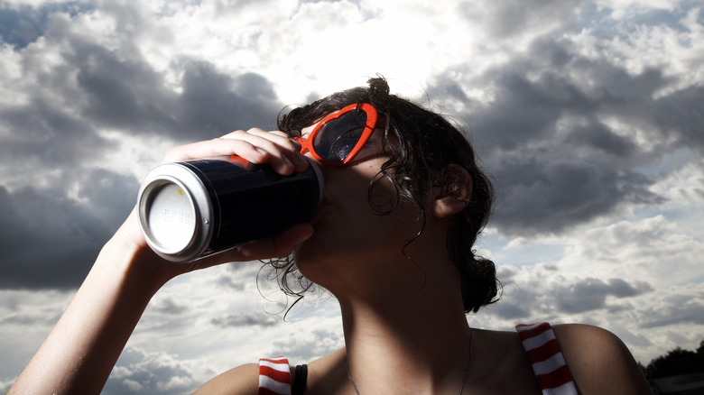 a woman drinking a beer out of a can