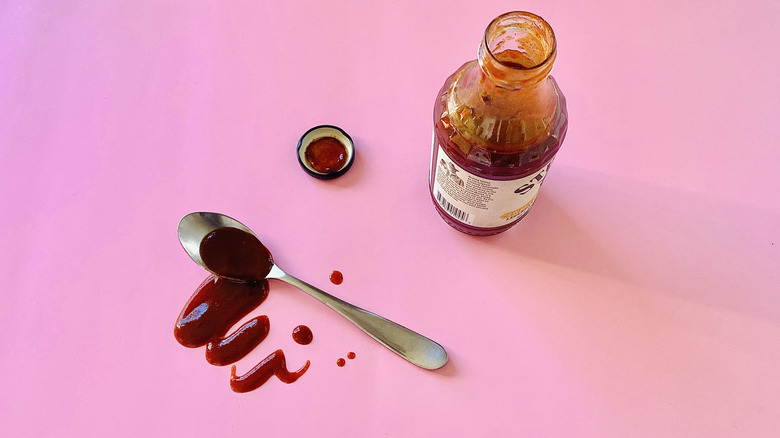 Open bottle of barbecue sauce with saucy spoon