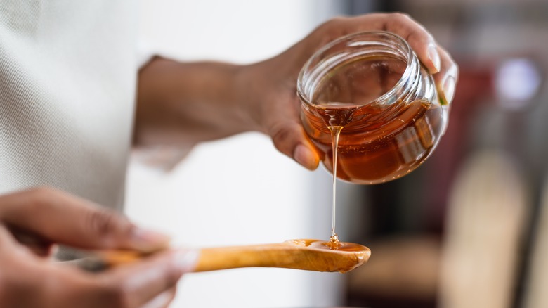 person pouring honey onto spoon