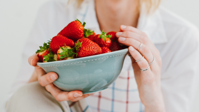 woman holding bowl of strawberries