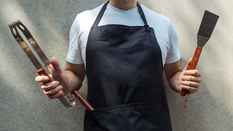 man holding barbeque utensils