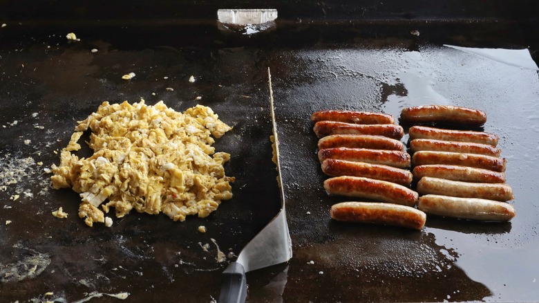 eggs and sausages separated on griddle