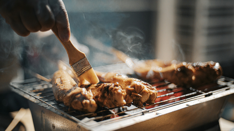 Chcken skewers being brushed with  marinade