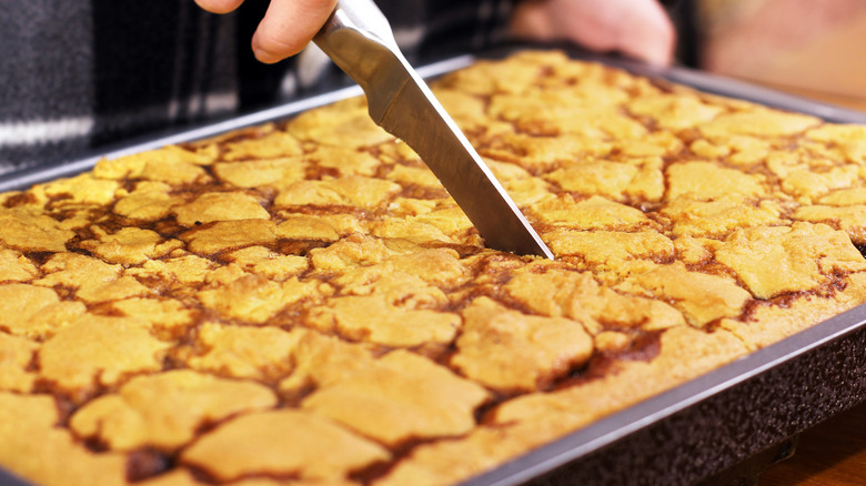 Yellow sheet cake being sliced