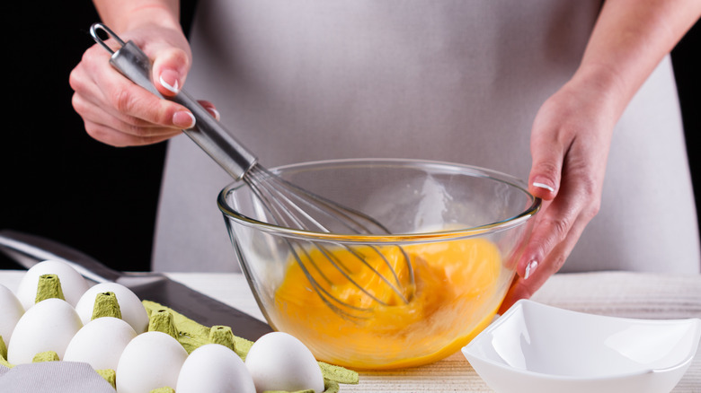 person whisking eggs in bowl